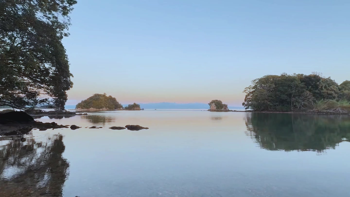 夕方、島影と淡い空を鏡のように映す海